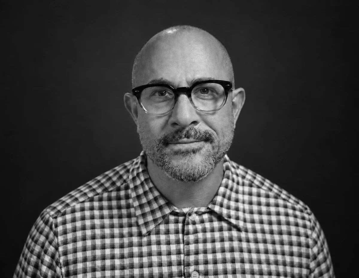 Black-and-white portrait of Omar Afra wearing glasses and a checkered shirt.