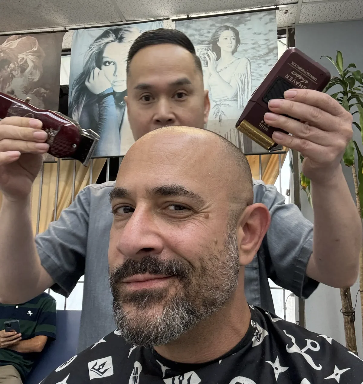 Omar Afra in a Houston barbershop chair with barber Danny Truong behind him holding clippers.