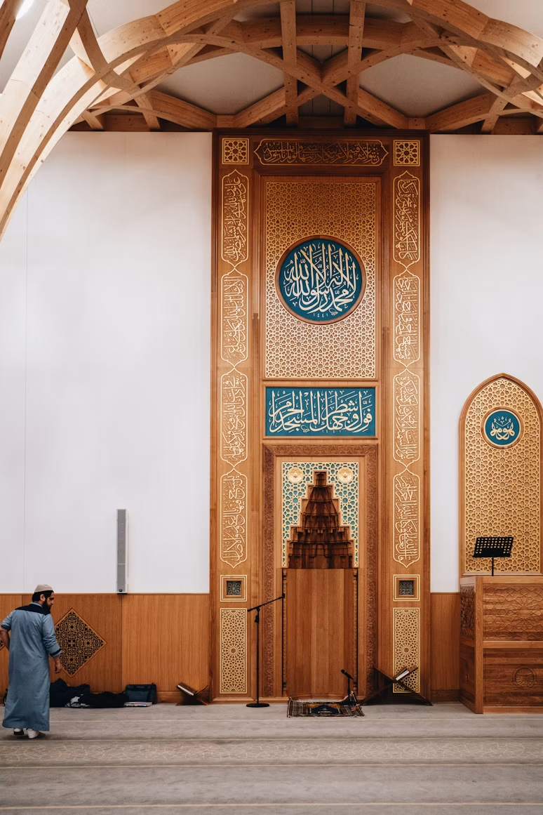 A wooden mosque mihrab with Arabic calligraphy and geometric detailing.