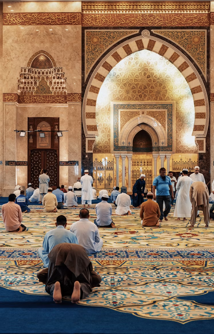 Worshippers gathered inside an ornate mosque prayer hall.