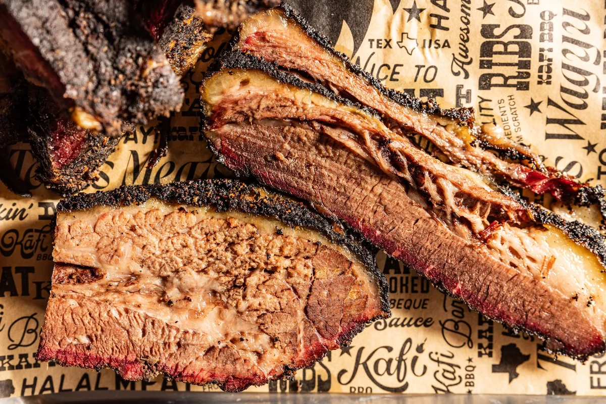 Sliced smoked brisket and beef ribs on Kafi BBQ branded paper.