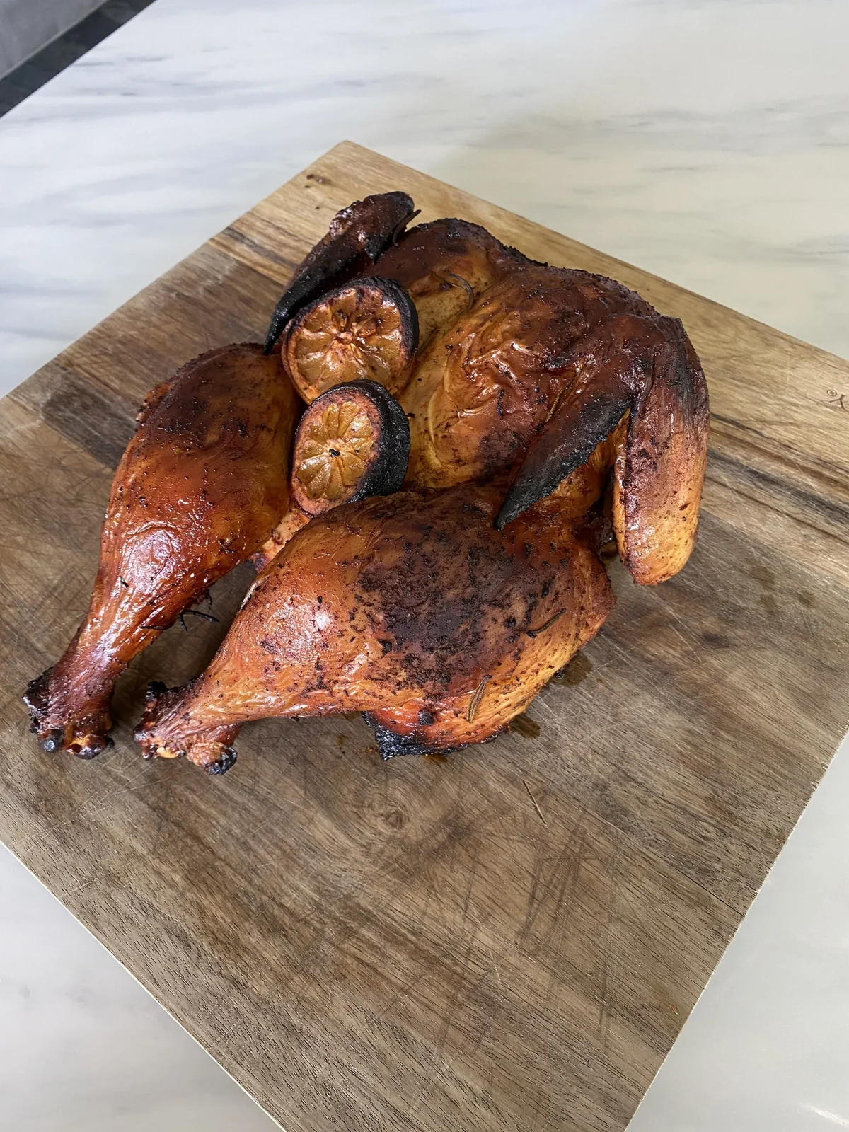 A whole smoked chicken on a wooden cutting board.