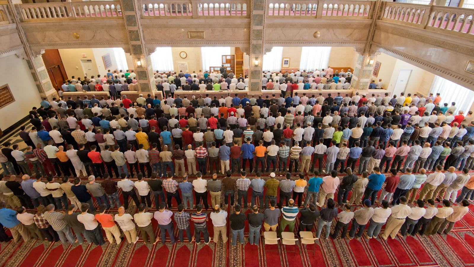 A large Muslim congregation standing together in prayer inside a mosque.