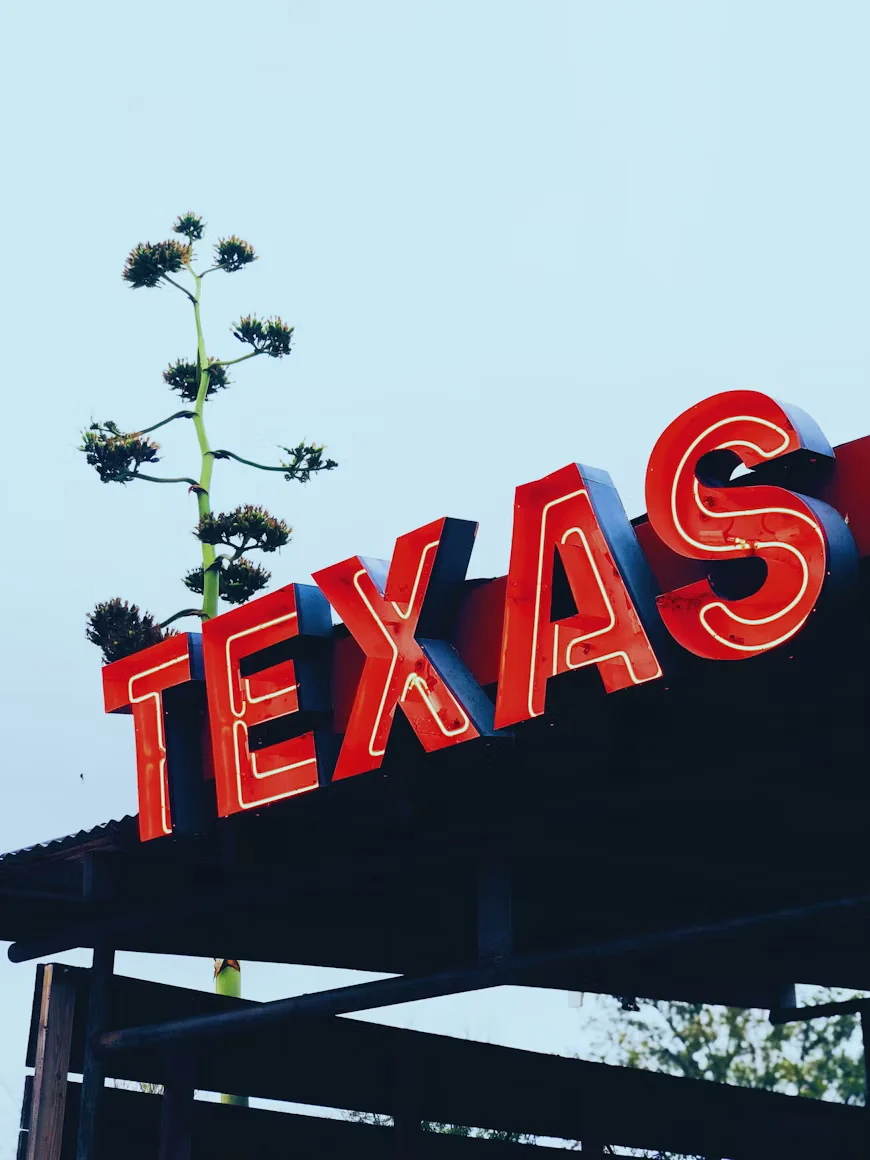 A red Texas sign photographed in daylight.