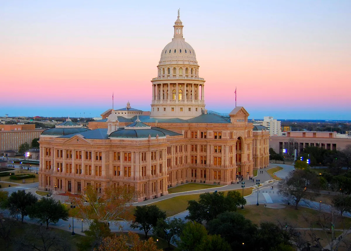 The Texas State Capitol building in Austin, with its central dome and surrounding grounds.